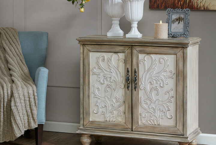 The Madison Park Driscoll 2-Door Cabinet offers a perfect blend of functionality and style for your home decor. This accent chest features a floral design on the cream-hued door panels that adds an elegant touch to the design. The natural-hued frame and legs complement the doors