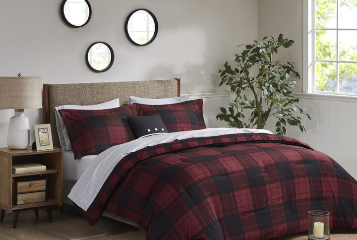 The Madison Park Essentials Everest Reversible Comforter Set with Bed Sheets brings a cozy cabin allure to your bedroom decor. A red and black buffalo check print adorns the front of the ultra-soft microfiber comforter