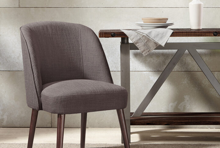 The soft curves of the wraparound back of this dining chair highlight the thin tapered legs