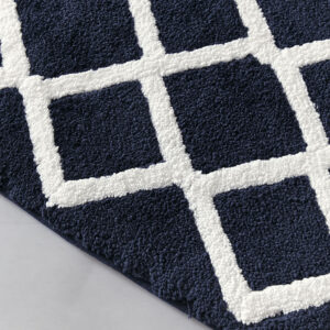 this high pile bath rug features a geometric fretwork design that flips to a classic border pattern