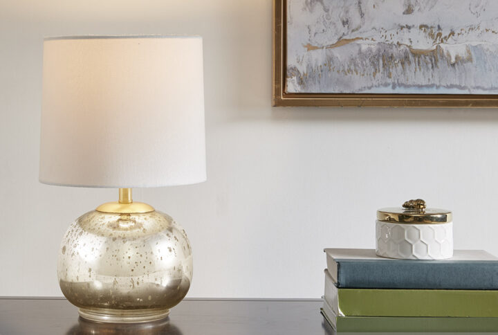 Illuminate your home with the 510 Design Saxony Metallic Glass Table Lamp. The elegant silver and gold glass base provides a touch of elegance and sophistication to any room. The base is complemented with a white drum shaped shade