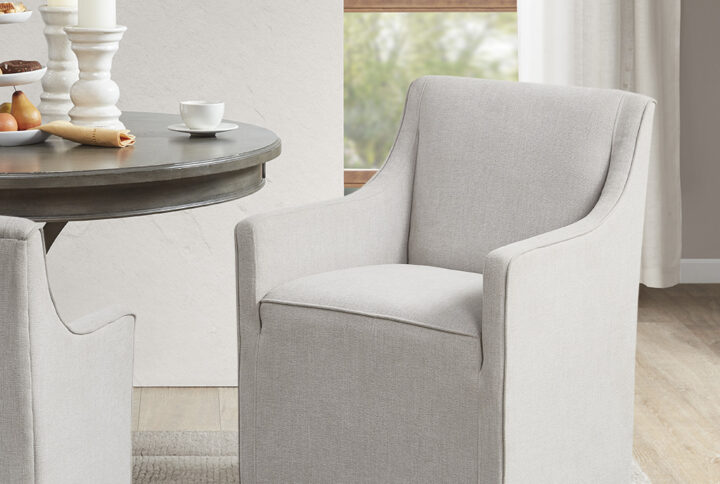 Elevate your dining space with the sleek style of Madison Park's Charlotte Upholstered Dining Arm Chair with Casters. This fully upholstered dining chair flaunts a tailored farmhouse design with its sloped arms