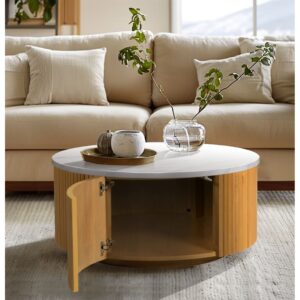 Elevate your living room with the INK+IVY Layana Round Coffee Table with Storage. This stylish faux white marble table exudes luxury in any modern setting with its drum shape and mixed materials design which blend effortlessly with a natural wood finish and reeded detailing on the fluted wooden base. The circle coffee table includes built-in storage with easy-to-access doors located on opposite sides