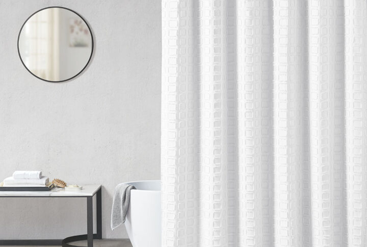 Elevate your bathroom decor with the Madison Park Metro Woven Clipped Solid Shower Curtain. This solid white shower curtain features a woven square geometric design with a clipped treatment to create beautiful texture and dimension