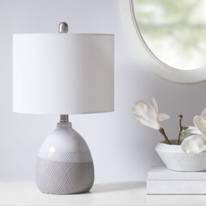 Update your space with the sleek style of the Driggs Ceramic Textured Table Lamp. The base is made from ceramic with a painted Ivory/Grey and white finish for a sleek gradient look. The drum shaped white shade softly filters the light