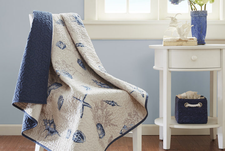 The Madison Park Bayside quilted throw creates a casual coastal look.  The throw features assorted seashells accentuated with light and dark blue coloring on an ivory background. In a deep taupe color