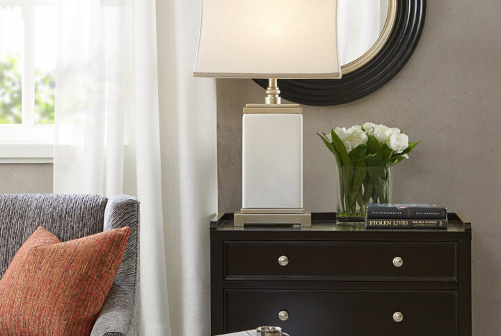 Bring a touch of elegance to any room in your home with the Hampton Hill Colette Ceramic Table Lamp. This rectangular table lamp features an ivory ceramic stand with an antique silver metal base and top to create a sophisticated transitional look. The off-white cotton shade softly filters the light into your room and is accented with a grey trim to complement the design. No assembly required.