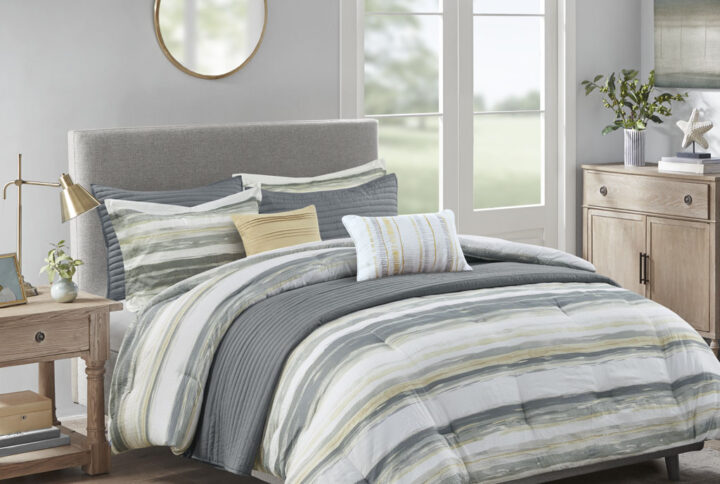 Create a relaxing and tranquil atmosphere in your bedroom with Madison Park’s Marina 8 Piece Printed Seersucker Comforter and Quilt Set Collection. The textured seersucker comforter features a watercolor stripe print in yellow and gray hues and a off white reverse