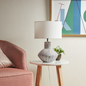 Make a statement with the modern style of the INK+IVY Agape Boho Ceramic Table Lamp. This round table lamp features a gourd-inspired base flaunts a geometric stripe pattern against the white finish to create a bold contrasting design. A round drum lamp shade acts as a soft light filter to create a warm ambiance