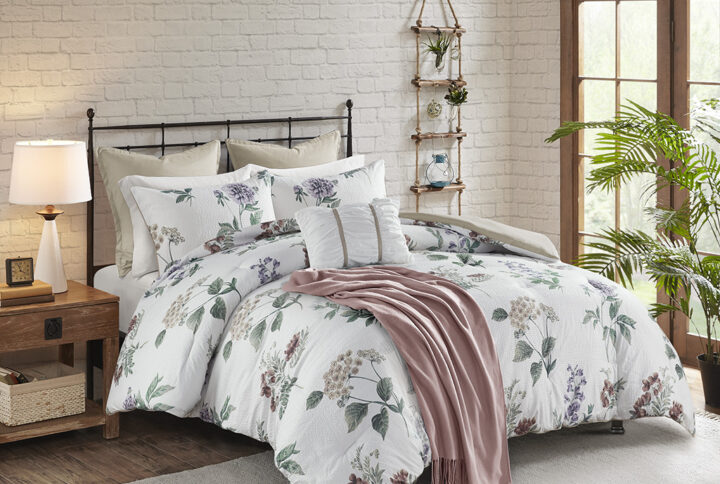 The Madison Park Zennia 7 Piece Printed Seersucker Comforter Set with Throw Blanket offers a charming farmhouse update for your bedroom. The textured seersucker comforter features an all-over floral print in soft blush and taupe hues on the white base