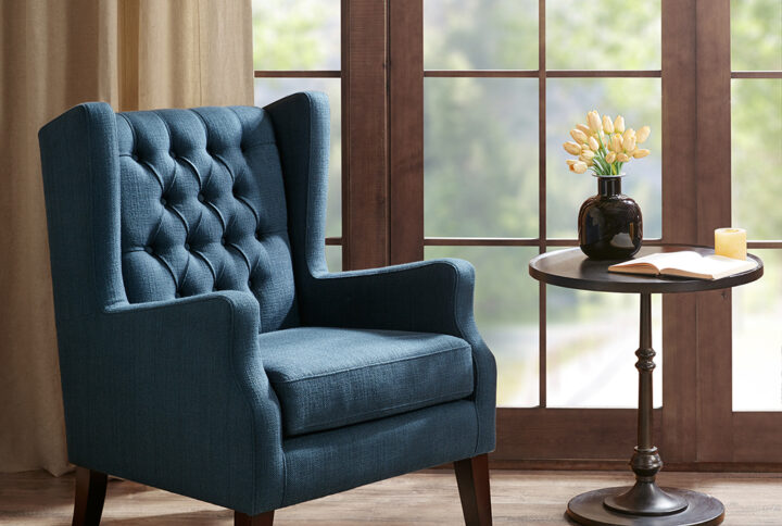 This classic wing chair with its button tufted detailing and sloped arms adds a casual twist with its navy casual woven fabric. Leg assembly required.