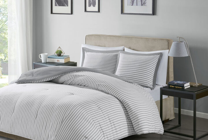 The Madison Park Essentials Hayden Reversible Down Alternative Comforter Mini Set gives your bedroom a fresh casual update. Sporting a grey striped pattern