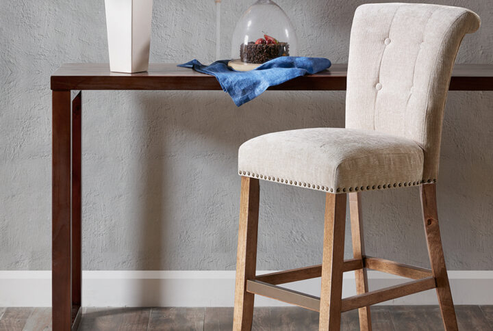 Elegant bronze nail heads add an extra touch of dignified style to this roll back button tufted bar stool. Assembly required.