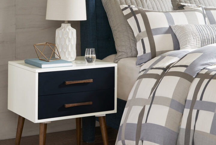 Transform your home with the striking style of the INK+IVY Jeremy Storage Nightstand. This rectangular nightstand features two pull-out drawers to easily store and keep your essential items within reach. The navy hues on the drawers are complemented by pecan wood handles and legs that stand out against the off-white frame. Create a stunning mid-century modern look in your bedroom with this handsome storage nightstand. Leg assembly is required.