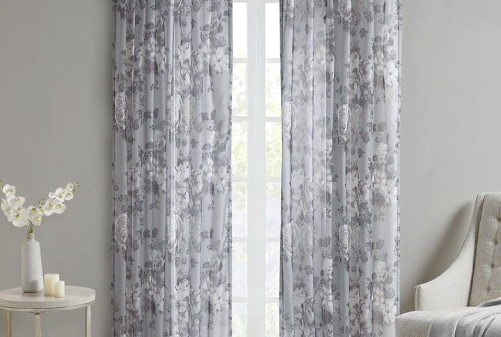 The Madison Park Simone Printed Floral Rod Pocket and Back Tab Top Voile Sheer brings a soft and romantic touch to your home decor. This voile sheer curtain panel features a beautiful mauve and neutral printed floral on a dark grey ground for a rich and stylish contrast