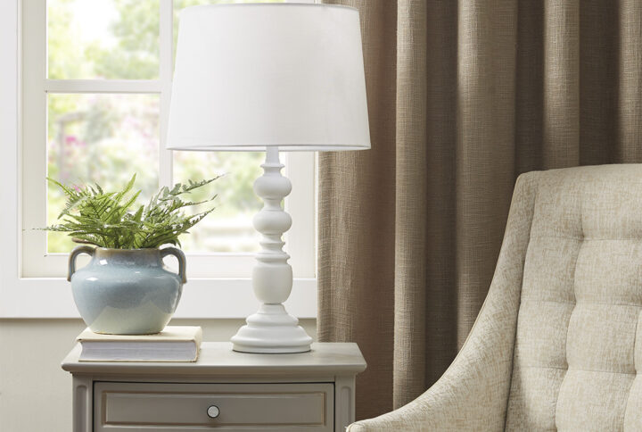 The Martha Stewart Astoria Resin Buffet Table Lamp offers a chic traditional update to your living room or bedroom. This table lamp features a resin frame in a matte white finish with a candle stick design to create a refined farmhouse look. The tapered lamp shade is made from linen to softly filter the light into your space and is not adjustable. This farmhouse table lamp also uses a rotary switch to find the right light setting and adds a subtle charm to your home decor. 1 Type-a light bulb is needed. Spot clean only. Comes with a 2-year warranty.