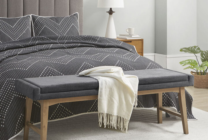 Complete your bedroom or entryway with the simple charm of the INK+IVY April Mid-Century Upholstered Accent Bench. This accent bench features a comfortable foam padded seat upholstered in a multi-hued grey fabric