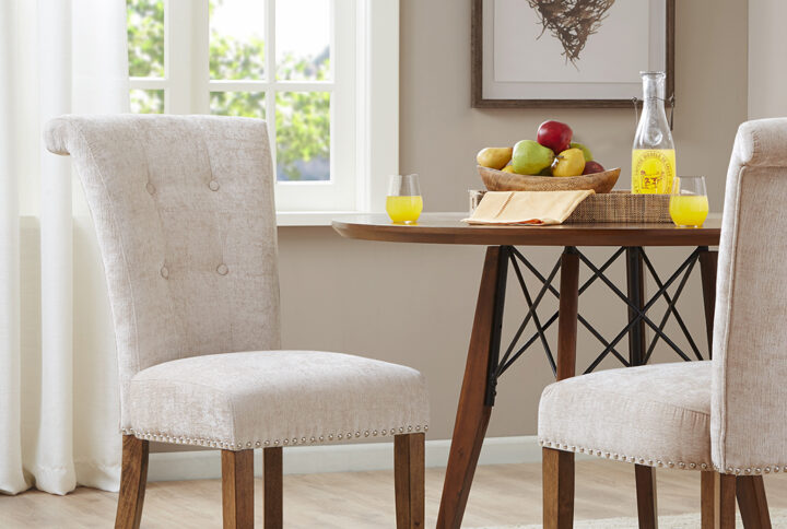 Elegant silver nail heads add an extra touch of dignified style to this roll back button tufted armless dining chair. Assembly required.