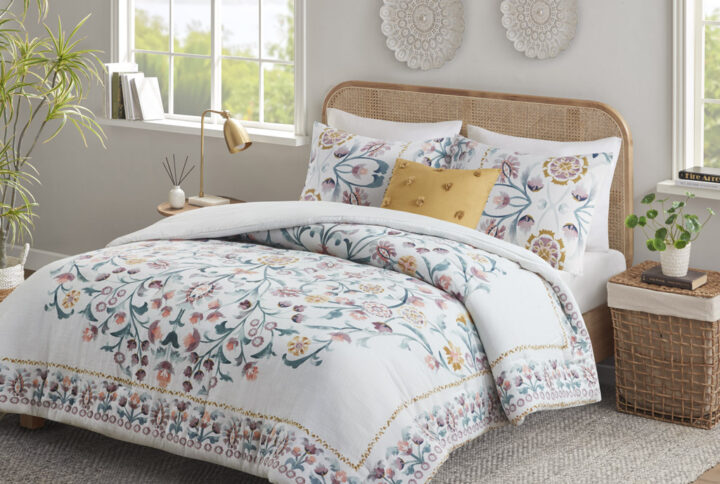 This shabby chic comforter set features a large floral print design in the center while blossoms line the edges of the comforter creating an enchanting border. Included with this set is one square decorative pillow with tufted pom poms for a touch of whimsical delight. Colors found in this bed set include various shades of teal