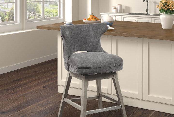 The Madison Park Emmett Swivel Counter Stool brings a chic combination of comfort and style to your kitchen. This counter stool features a low back and is upholstered in a rich charcoal fabric to create a stunning transitional look. The solid wood legs showcase a light grey finish to complement the upholstery. A pewter nail head trim on the open back adds an elegant touch to the design