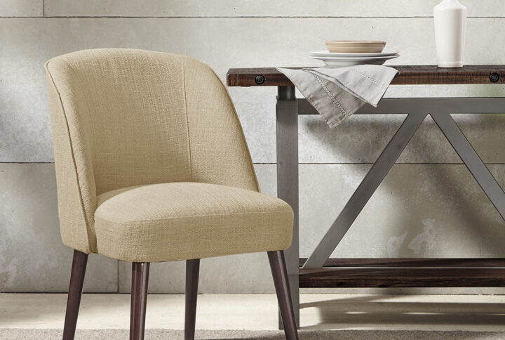 The soft curves of the wraparound back of this dining chair highlight the thin tapered legs