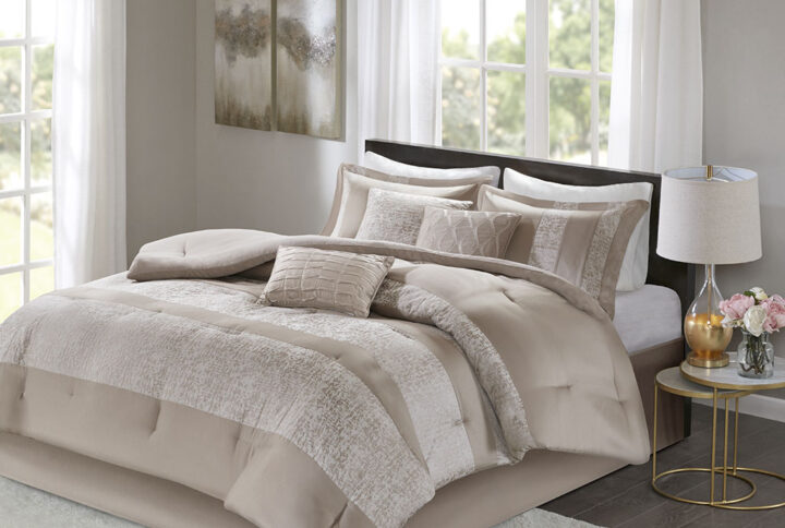 The Madison Park Ava 7 Piece Chenille Jacquard Comforter Set offers a luxurious update to your bedroom décor. The luxurious taupe comforter and shams flaunt a pieced design with stripes of textured chenille jacquard that creates a stunning three dimensional effect. The 2 square decorative pillows and one oblong pillow are stuffed with hypoallergenic filling and feature embroidery and pleating details that provide elegant touches for the top of the bed. A solid taupe bed skirt completes the comforter set