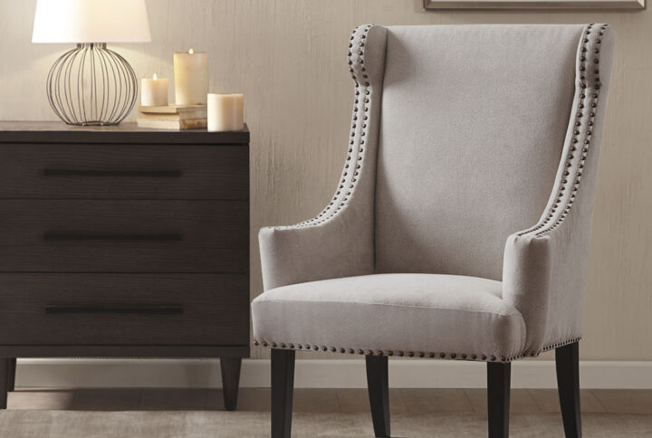 Add this stylish piece to your decorating mix as an updated accent wing chair with curved arms and double row nail head trim. Featured in a mushroom color with taupe tones. Leg assembly required.