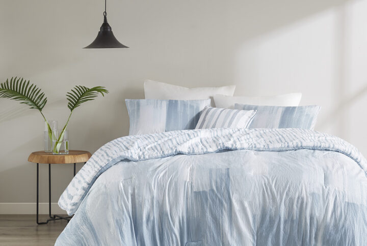 The N Natori Brush Stroke 4 Piece Reversible Seersucker Comforter Set elevates your bedroom with its simple and elegant lounge style. This reversible comforter flaunts a soft blue