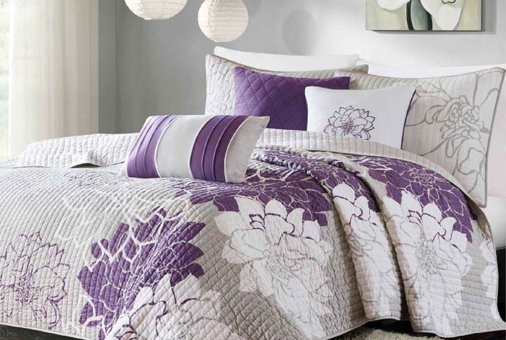 The Madison Park Lola 6 Piece Reversible Cotton Printed Coverlet Set transforms your bedroom into a beautiful and graceful space. A gorgeous floral print in a soft white and purple hue pops against the solid light grey ground cotton coverlet and shams for a stunning transitional look. Three decorative pillows with embroidered details and fabric manipulation add texture and dimension to the bed