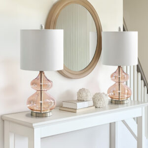 The 510 Design Ellipse Table Lamp Set brings modern elegance to any space. This set of 2 lamps features double-stacked gourd-shaped glass bases with polished surfaces and brushed gold metal accents. The translucent glass softly diffuses light for a warm