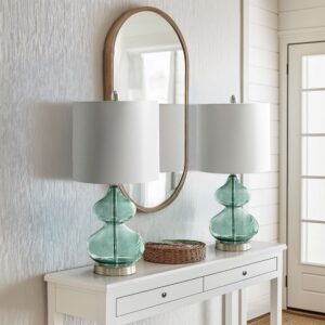 The 510 Design Ellipse Table Lamp Set brings modern elegance to any space. This set of 2 lamps features double-stacked gourd-shaped glass bases with polished surfaces and brushed silver metal accents. The translucent glass softly diffuses light for a warm