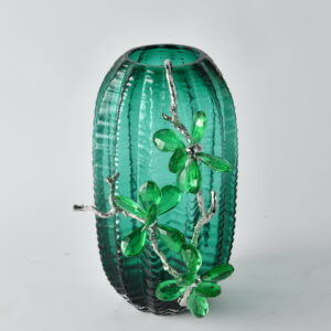Add a burst of vibrant elegance to your space with the Vibrant Emerald Charm Vase. This smaller version of our Emerald Garden vase features a textured green glass body paired with brilliant crystal flower embellishments and sculpted silver branches. Perfect as a standalone accent or paired in a collection