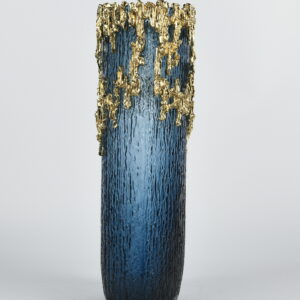 this cylindrical vase is crowned with a dramatic cascade of molten gold detailing that shimmers like liquid metal. Perfect for elevating floral arrangements or standing alone as a sculptural showpiece. Turn any room into a gallery of style with this high-impact vase that blends glamor