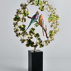 Capture the serenity of nature with the Songbird Garden Ring Sculpture. This enchanting piece features two vibrantly jeweled birds perched within a circular vine of glistening leaves